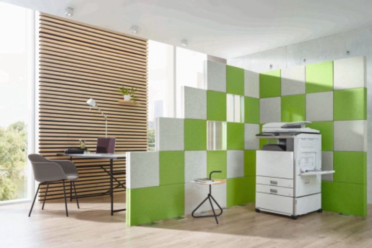 Tabique modular en ángulo de 90 grados en color gris y verde para aislar acústicamente una zona de fotocopiadoras en una oficina. Clase absorción de ruido A